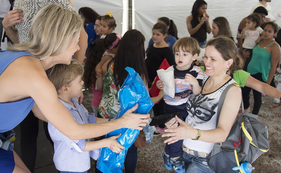 A mom and her kid giving presents to at a charity event